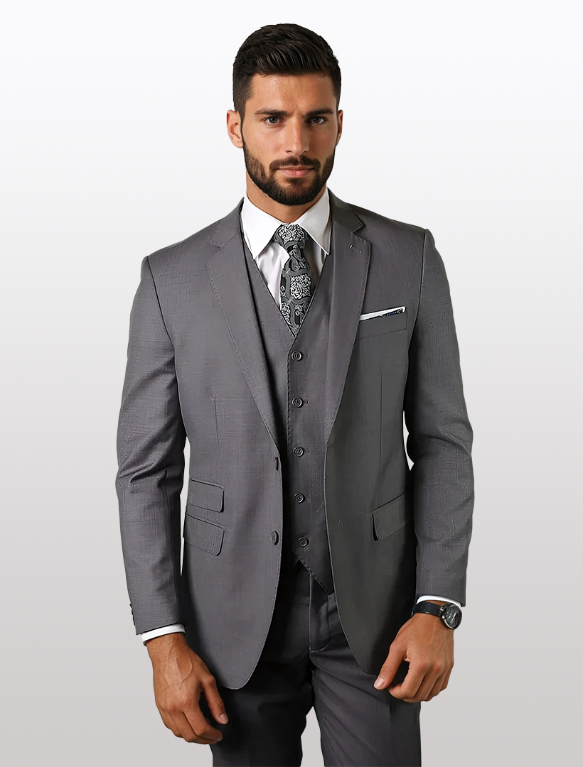 A man in a Statement Men's Solid Grey Tailored Fit 100% Wool Vested Suit and patterned tie stands against a plain white background.