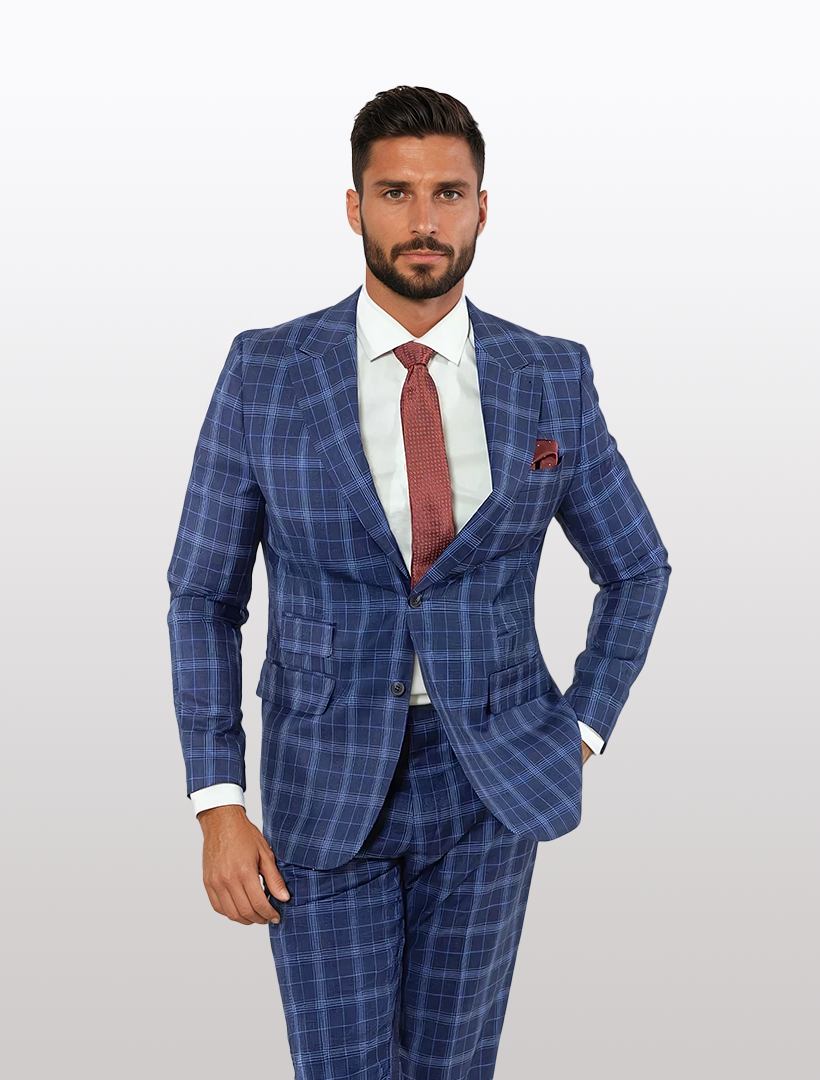 A man in a FUBU Blue Tartan Peak Lapel 2-Piece Suit paired with a white shirt and red tie stands against a light gray background.