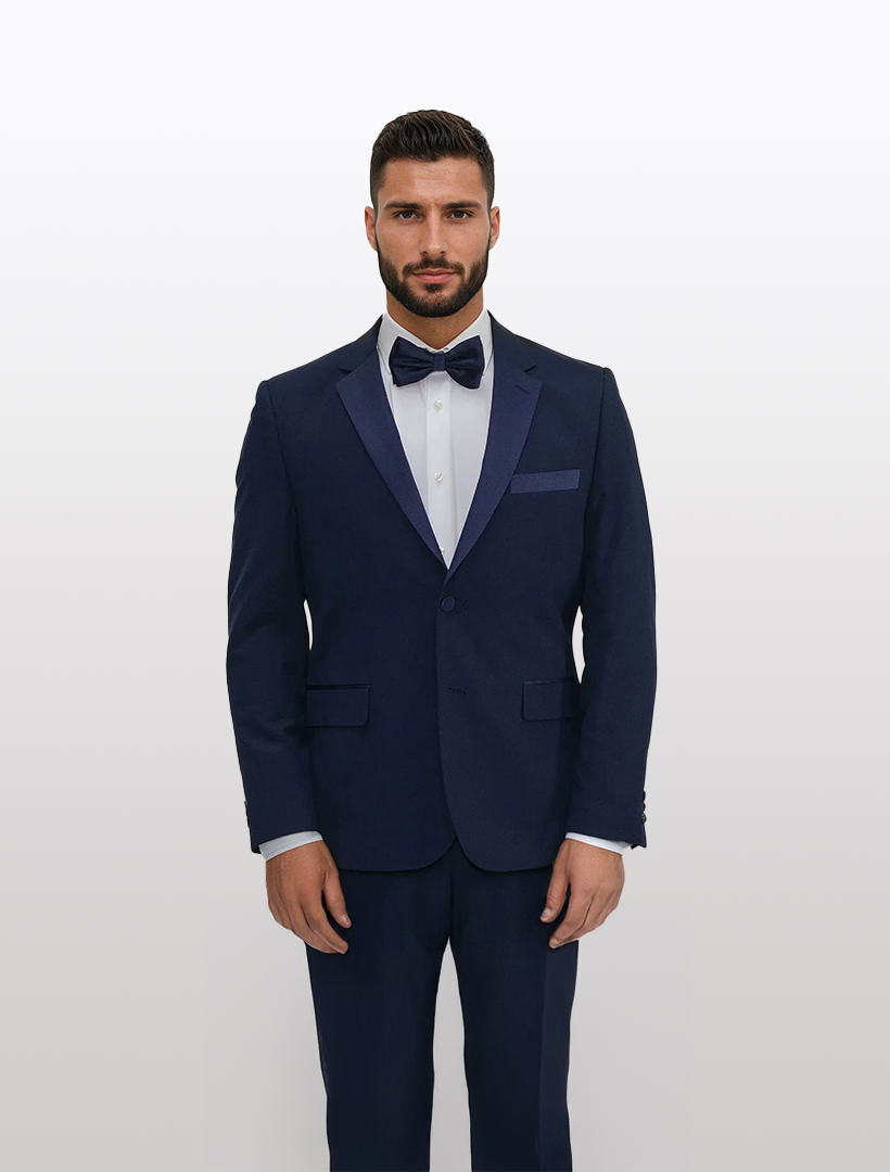 A man in a FUBU Classic Notch Lapel Navy Slim-Fit Tuxedo from Fubu The Colle, made of Tetron Rayon, stands with a bow tie against a plain white background.