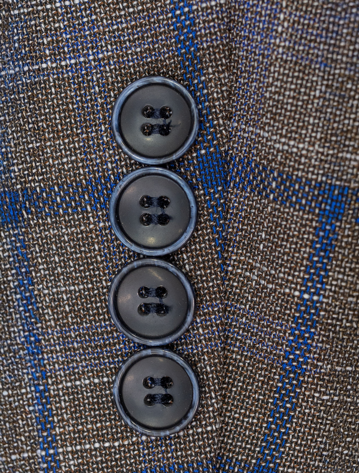 Close-up of four dark buttons on the FUBU Cedar Brown with Royal Blue Windowpane Sport Jacket by Fubu The Colle, highlighting the intricate brown and blue checkered pattern.