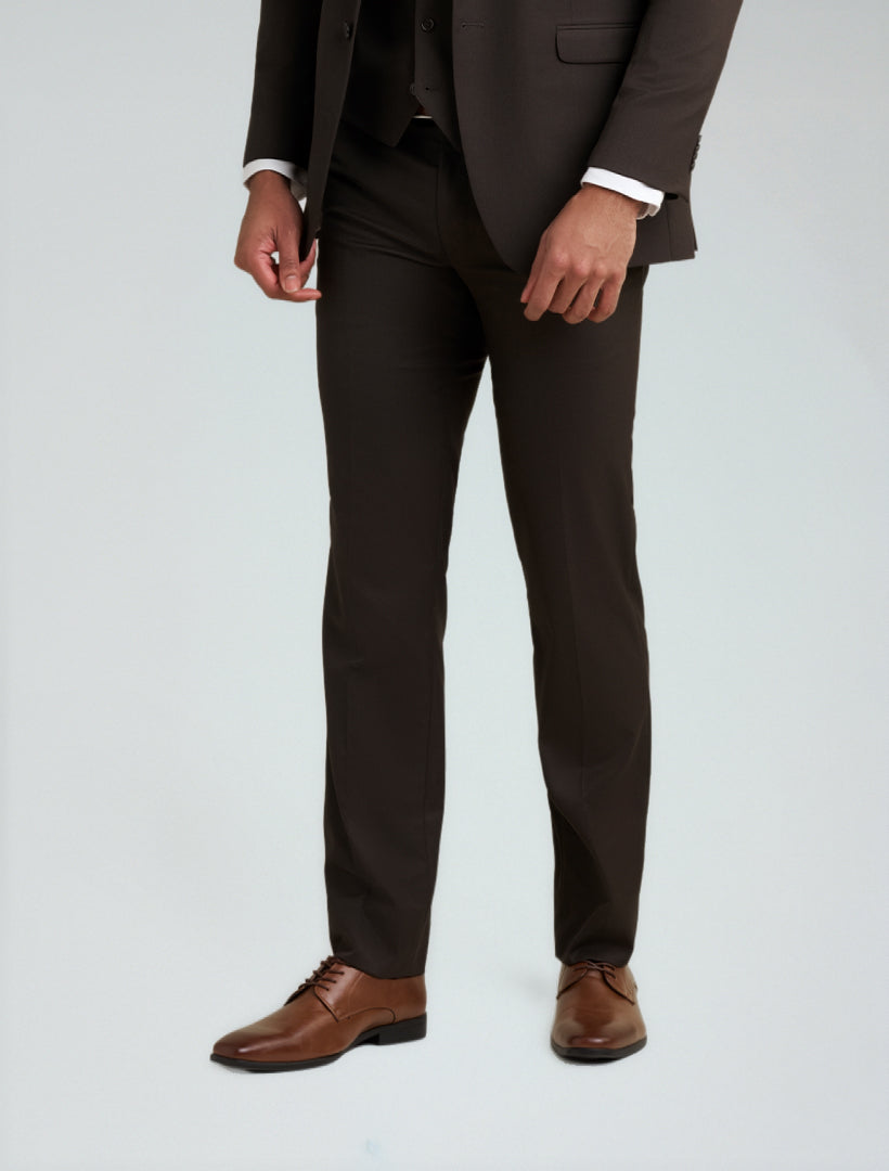 A man wears Allure Men's Brown Tailored Fit Dress Pants with a matching jacket, white shirt, and brown shoes, standing against a light gray background.