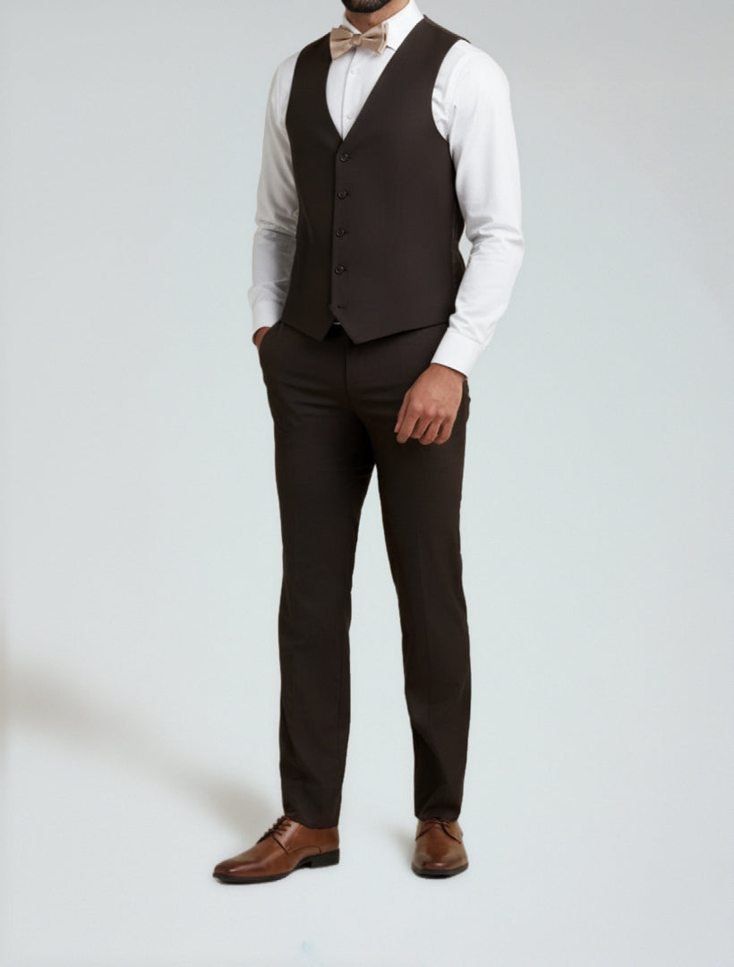 A man wears the Allure Men's Brown Tailored Fit Vest with a matching jacket and pants, white dress shirt, tan bow tie, and brown dress shoes, standing with one hand in his pocket against a plain background.