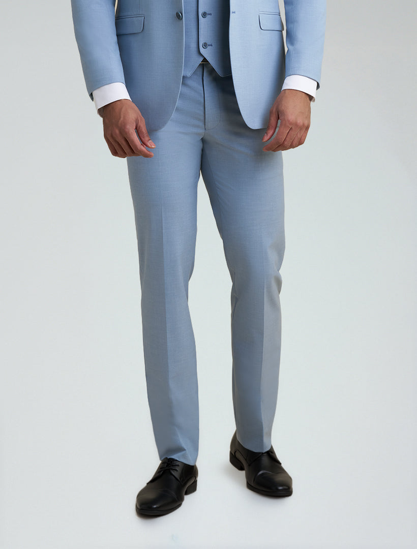 A person stands against a plain background wearing Allure Men's Light Blue Tailored Fit Dress Pants, styled with a matching suit jacket, white shirt, and black dress shoes.
