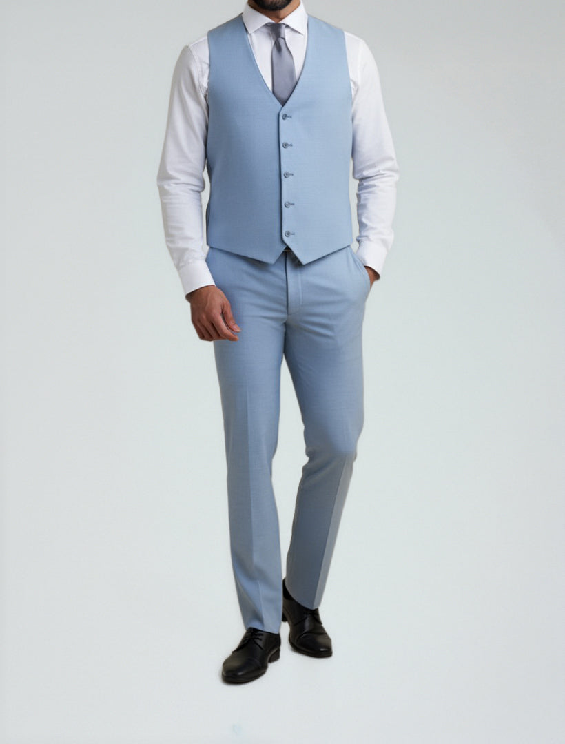 A man models the Allure Men's Light Blue Tailored Fit Vest with matching pants, white dress shirt, light gray tie, and black dress shoes against a plain light background.