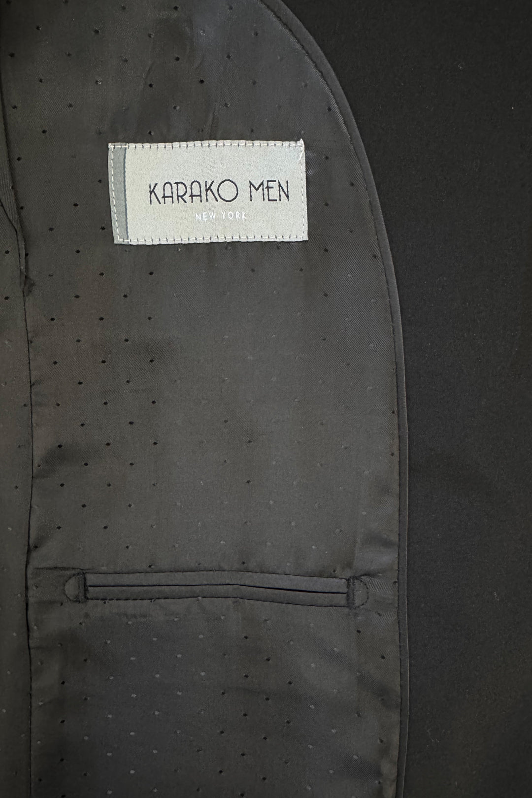 Close-up of the inside lining of a Karako Men Mens Black Suit jacket, featuring the brand label above a small pocket.