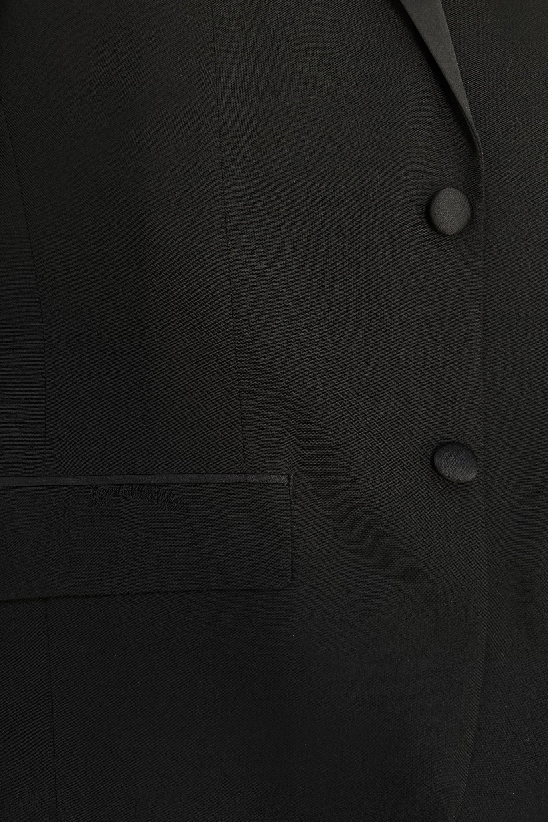 Close-up of the FUBU Classic Notch Lapel Black Tuxedo by Fubu The Colle, featuring a slim fit design with two buttons, part of a pocket, and elegant satin lapels.