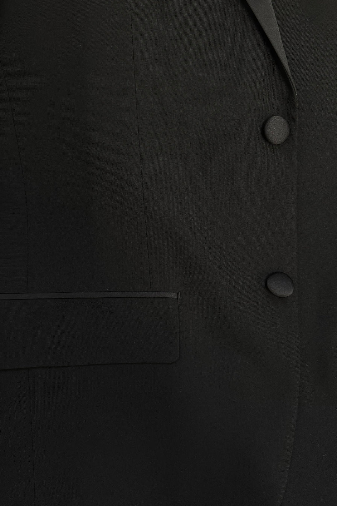 Close-up of the FUBU Classic Notch Lapel Black Tuxedo by Fubu The Colle, featuring a slim fit design with two buttons, part of a pocket, and elegant satin lapels.