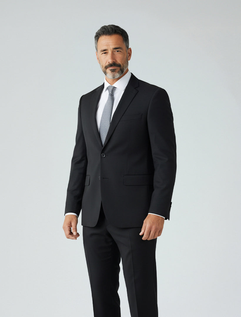 A man with salt-and-pepper hair and a beard is wearing the Karako Men Mens Black Suit with a white shirt and gray tie, standing in front of a plain light background.