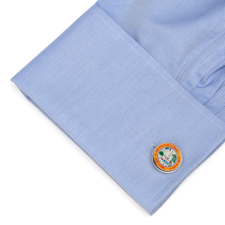 A light blue dress shirt cuff fastened with Florida Seal Cufflinks displaying the State of Florida seal.