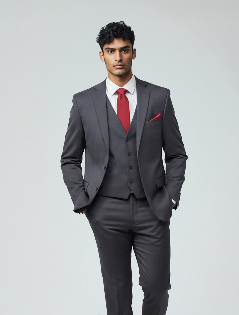 A man stands with his hands in his pockets against a plain light background, dressed in a Charcoal Grey Men's Slim-Fit Suit Separates Jacket by Karako Separates, paired with a white shirt, red tie, and matching red pocket square.