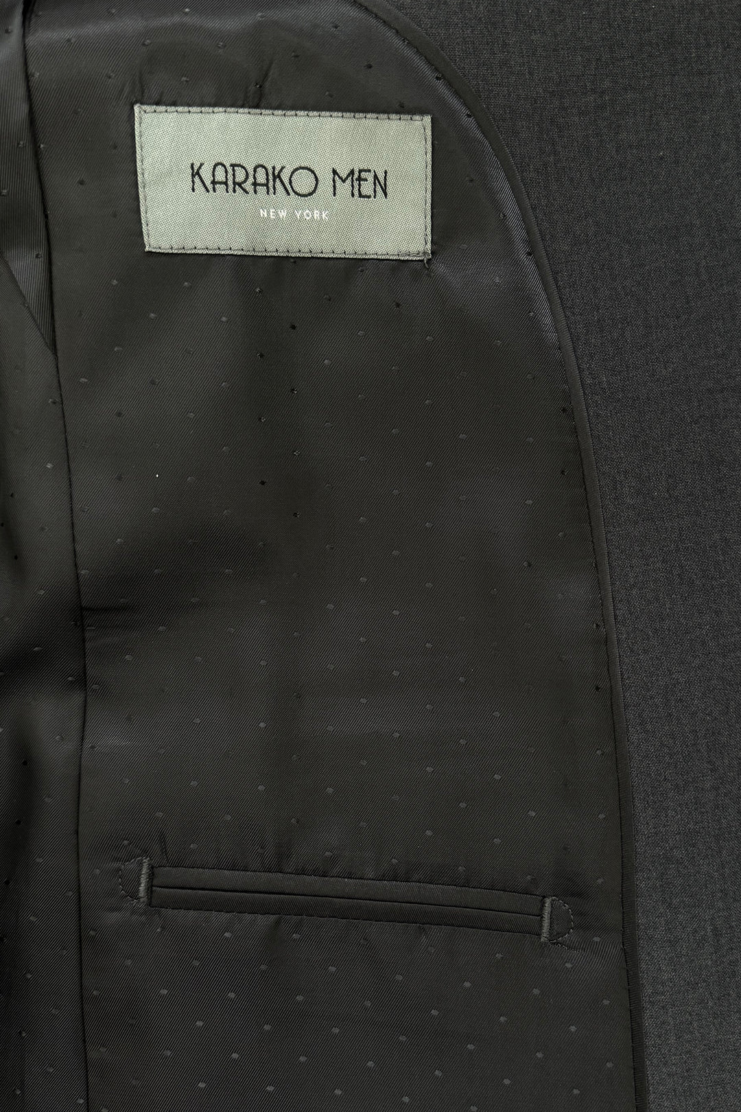 Close-up of the inside lining of a Mens Charcoal Suit by Karako Men, showing a label with the brand name above an interior pocket.