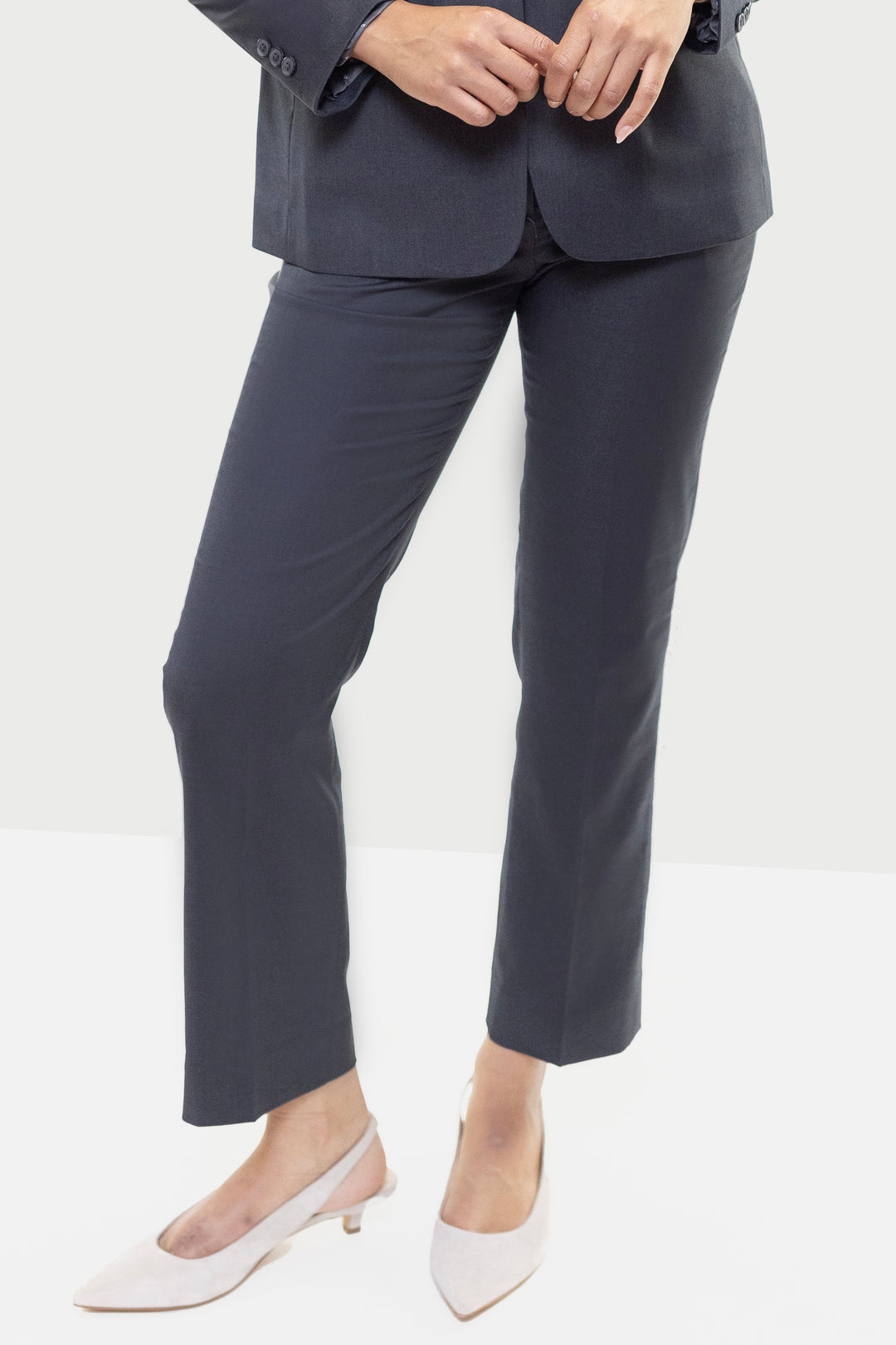 A person is standing in a tailored dark suit by Couture 1910, consisting of Women&