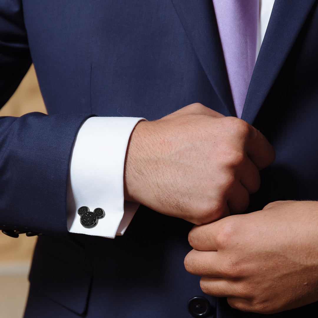 A man wearing a blue suit jacket and a white dress shirt, fastened with Disney Mickey Mouse Stainless Steel Black Pave Crystal Cufflinks.