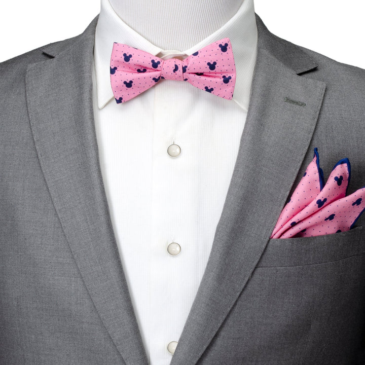A grey suit jacket and white shirt paired with a Disney Mickey Mouse Pink Dot Silhouette Pre-Tied Bow Tie and matching pocket square, both featuring a pattern of small blue silhouettes.