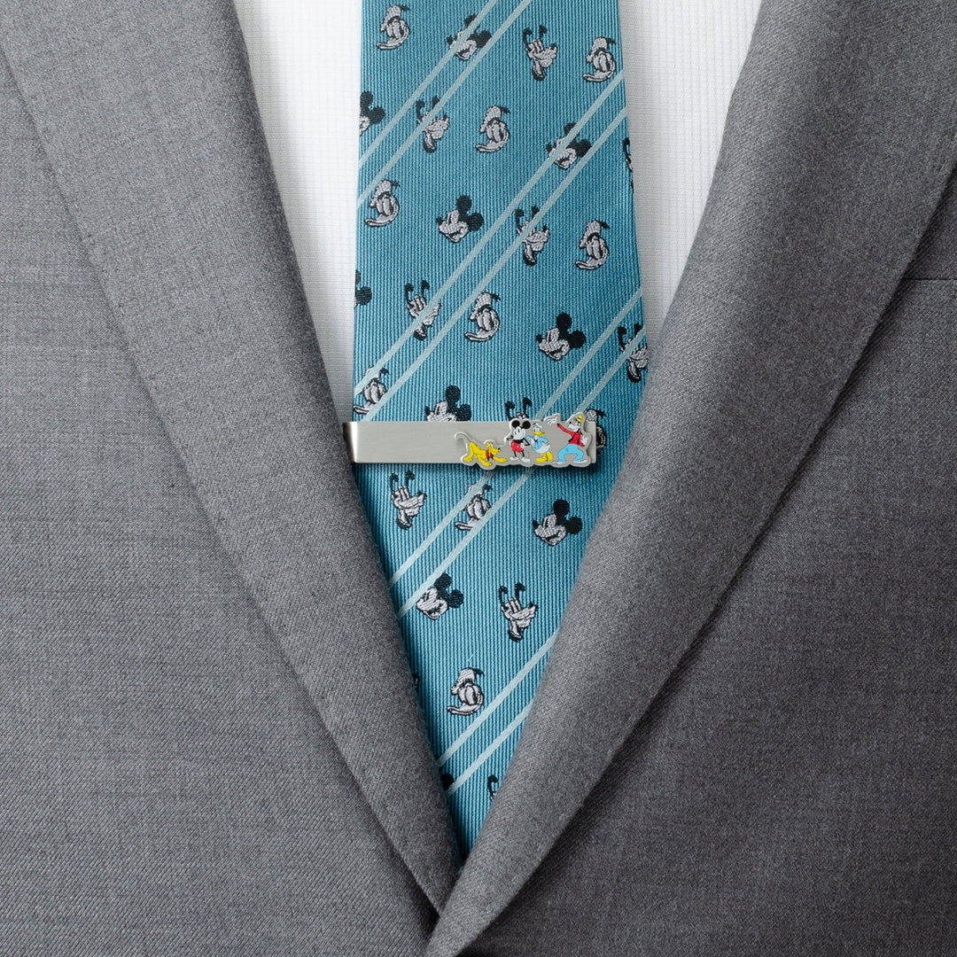 Disney Mickey and Friends Printed Silver Tie Bar clipped to a blue, patterned tie worn with a gray suit jacket.