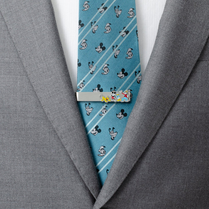 Disney Mickey and Friends Printed Silver Tie Bar clipped to a blue, patterned tie worn with a gray suit jacket.