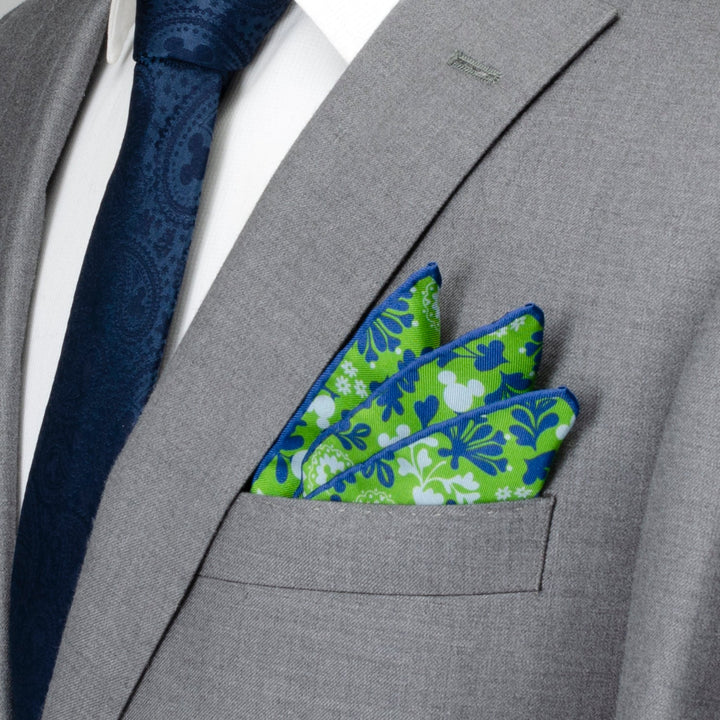Disney Mickey Mouse Floral Green Pocket Square with a floral pattern and hidden Mickey silhouettes, tucked into the breast pocket of a gray suit jacket.