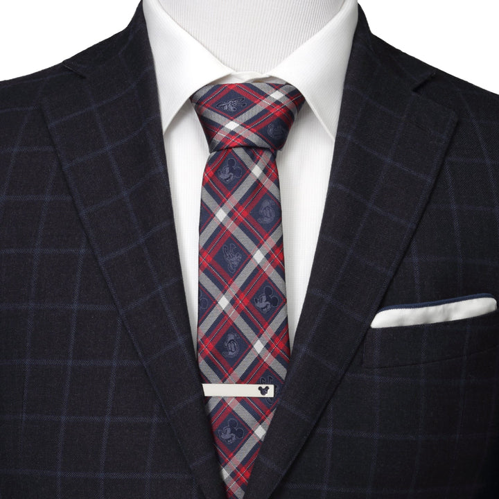 A man wearing a navy plaid suit, white shirt, and a Disney Mickey and Friends Navy Plaid Men’s Tie secured by a silver tie bar with a Mickey Mouse icon.