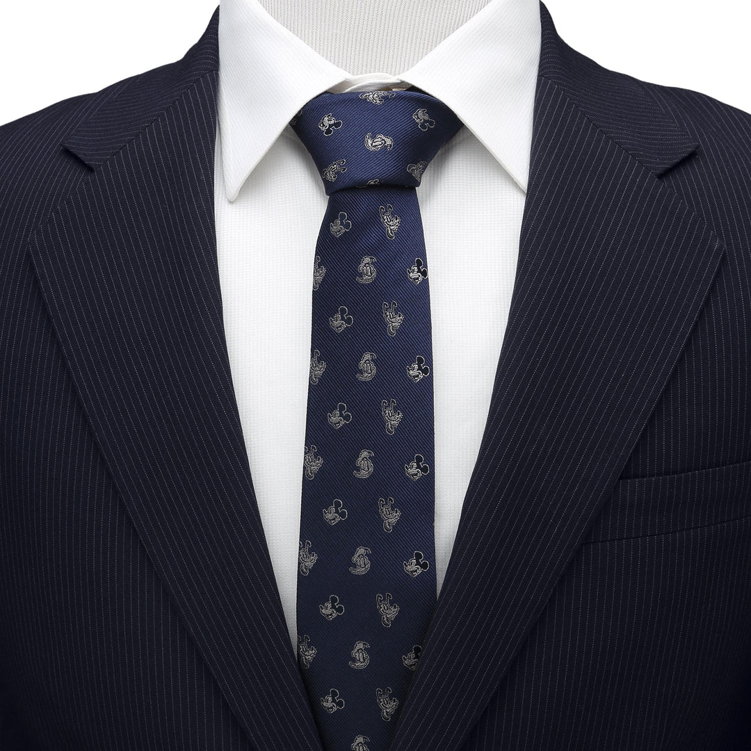 Disney Mickey and Friends Blue Men’s Tie in dark blue 100% silk with a repeating gold Mickey Mouse icon pattern, worn with a white collared shirt and pinstriped suit jacket.