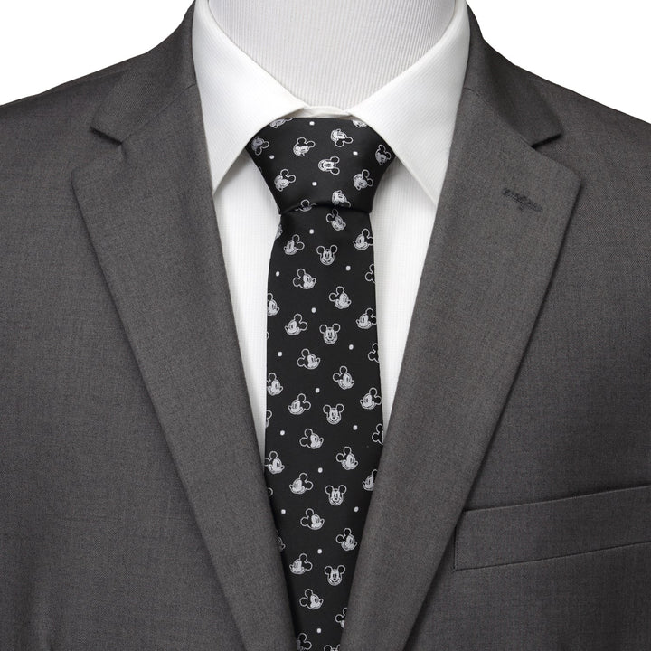 A Disney Mickey Mouse Black Dot Men’s Tie patterned with white heads and dots, worn with a white dress shirt and a grey suit jacket.