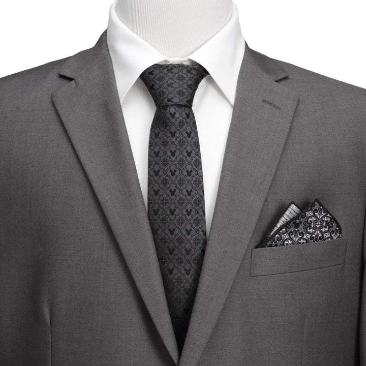 A Disney Mickey Mouse Pattern Black Men’s Tie worn with a white dress shirt, grey suit jacket, and a patterned pocket square.