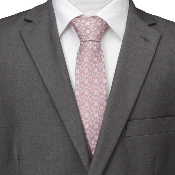 A Disney Mickey Mouse Silhouette Blossom Pink Men’s Tie with a white floral and Mickey Mouse silhouette pattern, worn with a white dress shirt and a grey suit jacket.