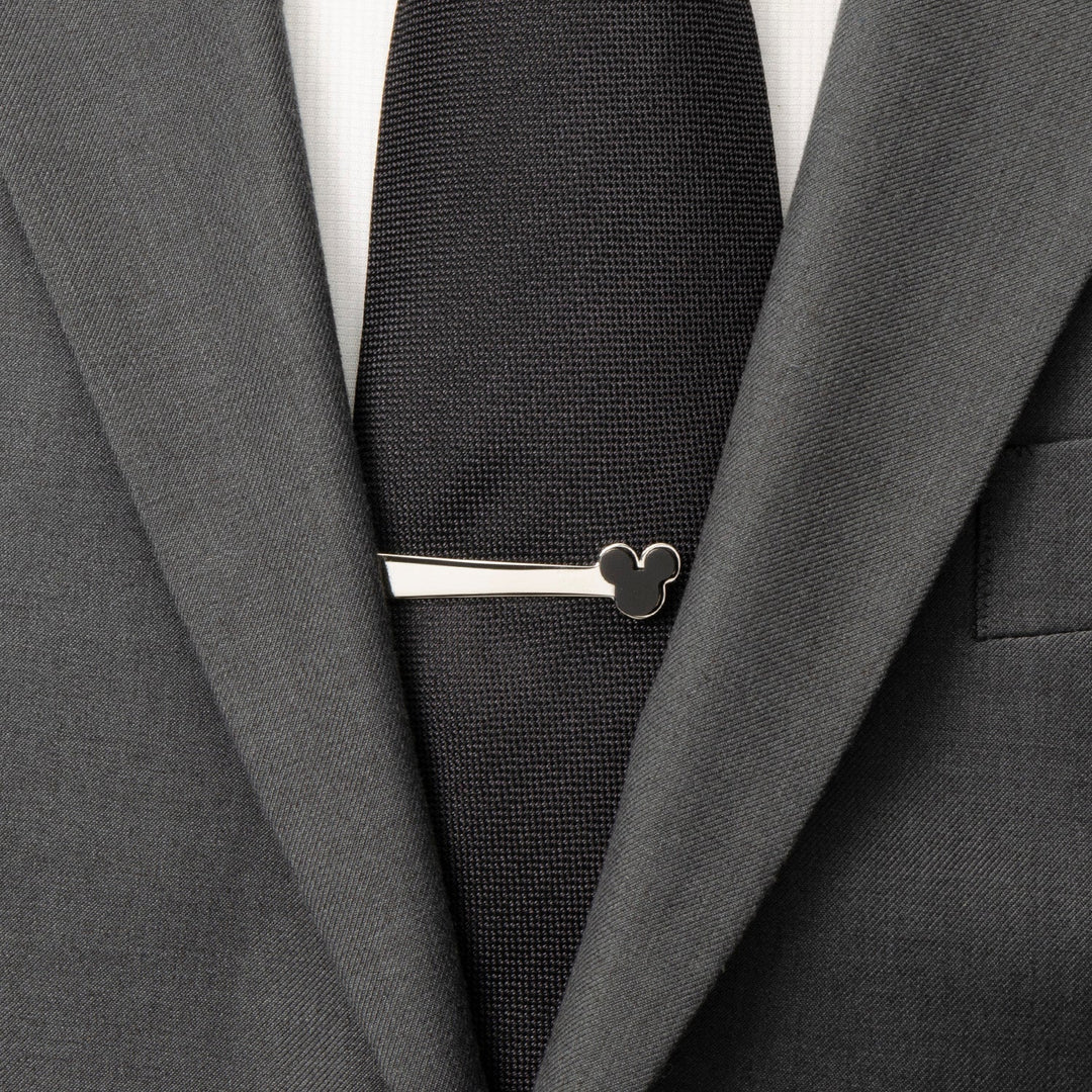 A silver-toned stainless steel Disney Mickey Mouse Onyx Stainless Steel Tie Bar worn on a black tie and grey suit.