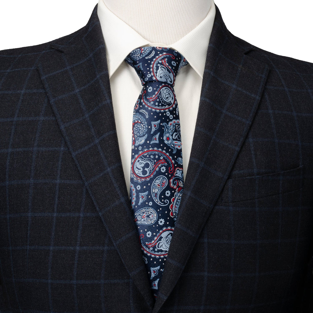 Disney Mickey and Friends Paisley Blue Multi Men’s Tie in dark blue with a white and red paisley pattern featuring hidden Mickey silhouettes, worn with a white shirt and a dark plaid blazer.