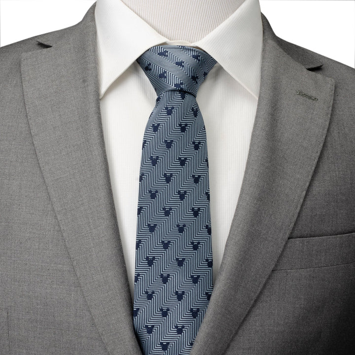 Disney Mickey Mouse Silhouette Blue Herringbone Men’s Tie in blue silk with geometric Mickey silhouettes, worn with a white dress shirt and grey suit jacket.