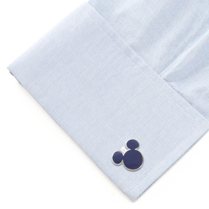 A circular, navy Disney Mickey Mouse Silhouette Blue Cufflink attached to a light blue dress shirt cuff.