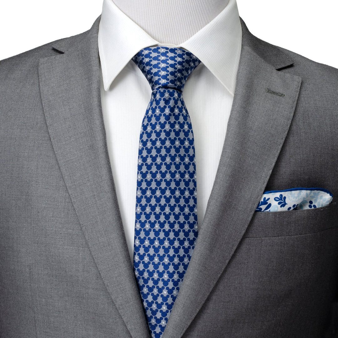 A Disney Mickey Mouse Silhouette Pattern Dot Blue Tie paired with a white shirt, grey suit jacket, and a floral pocket square.