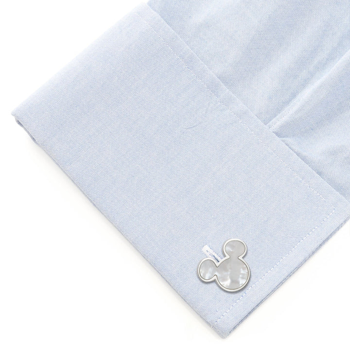 A silver-toned Disney Mickey Mouse Mother of Pearl Cufflink fastened to a light blue dress shirt cuff.
