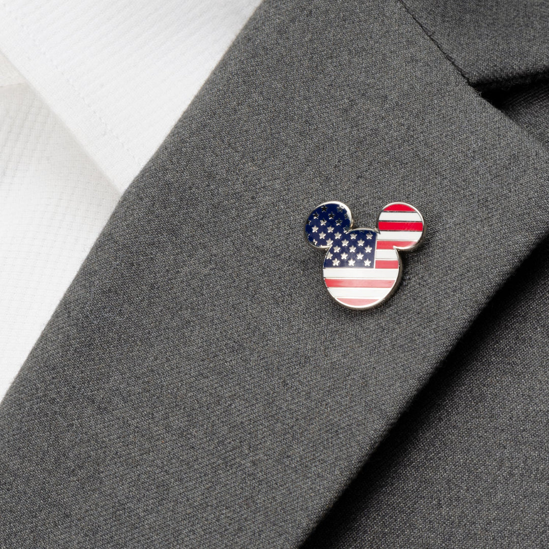 A Disney Mickey Mouse Stars and Stripes Lapel Pin with an American flag pattern attached to a gray suit jacket.