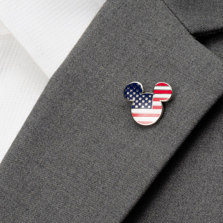 A Disney Mickey Mouse Stars and Stripes Lapel Pin with an American flag pattern attached to a gray suit jacket.