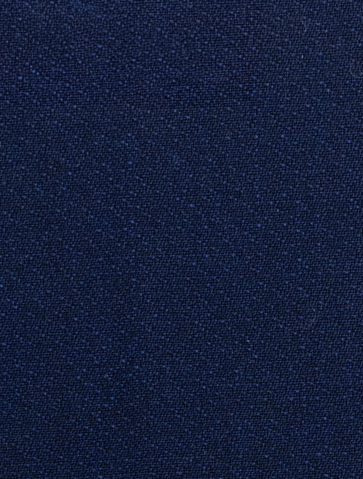 Close-up of the FUBU Indigo Solid fabric from the Peak Lapel 2-Piece Suit by Fubu The Colle, featuring a dark blue texture with a subtle weave pattern, ideal for crafting a slim fit suit.
