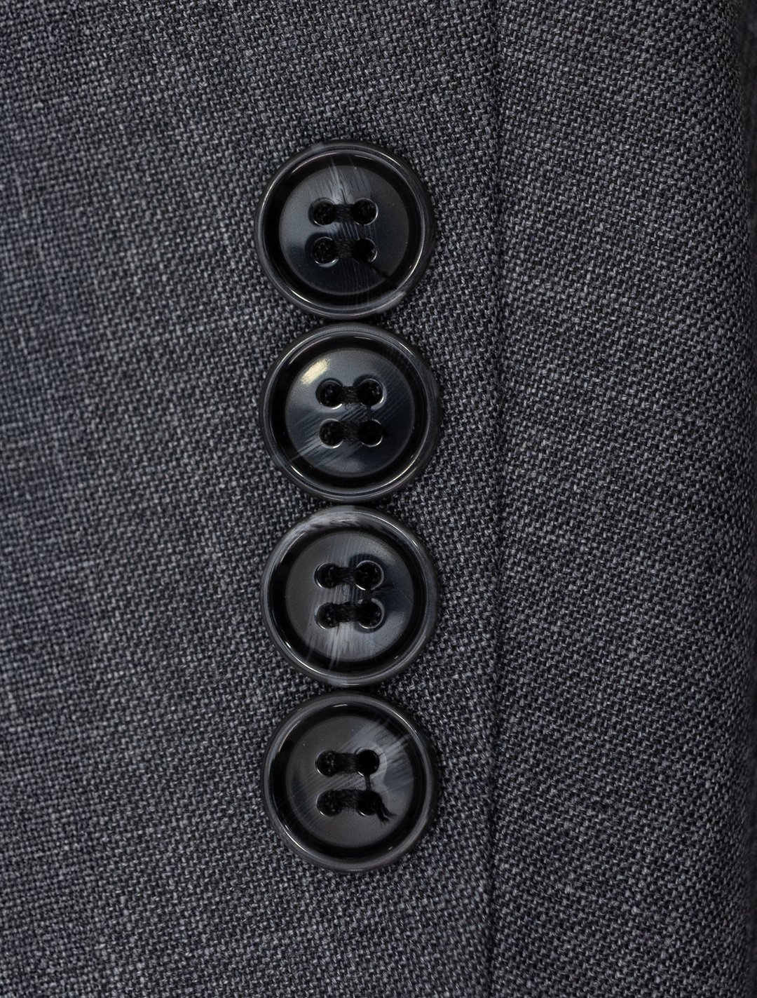 Close-up of four black buttons on the sleeve of a Fubu The Colle Iron Grey Peak Lapel 2-Piece Suit.