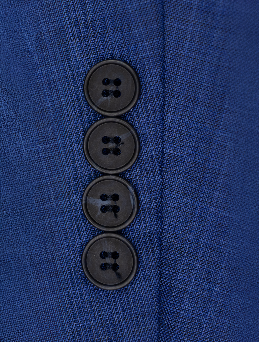 Close-up of four black buttons sewn vertically on the sleeve of the FUBU Cobalt Blue Peak Lapel 2-Piece Suit by Fubu The Colle, showcasing its refined detail and modern fit.