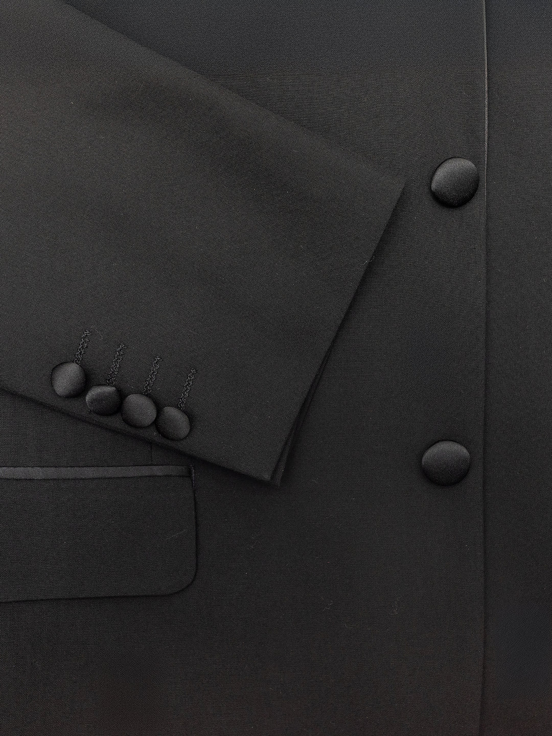 Close-up of the FUBU Classic Notch Lapel Black Tuxedo by Fubu The Colle, featuring a modern fit with satin lapels and a three-button sleeve design, complete with pockets and front buttons.