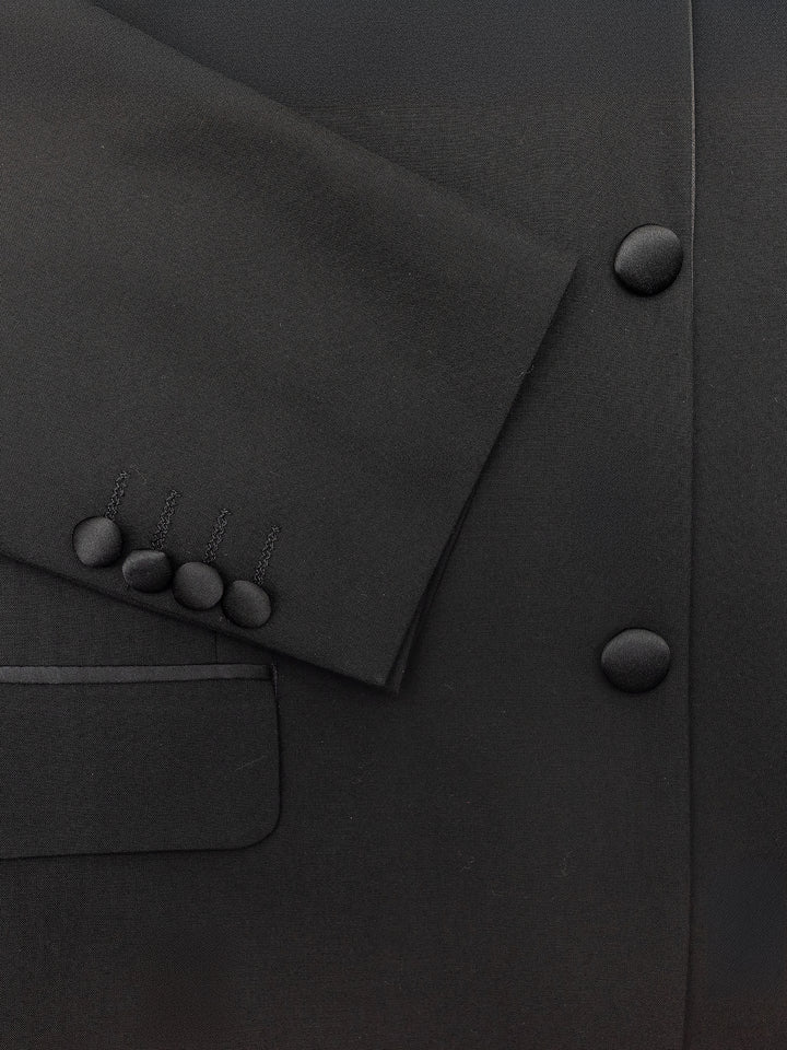 Close-up of the FUBU Classic Notch Lapel Black Tuxedo by Fubu The Colle, featuring a modern fit with satin lapels and a three-button sleeve design, complete with pockets and front buttons.