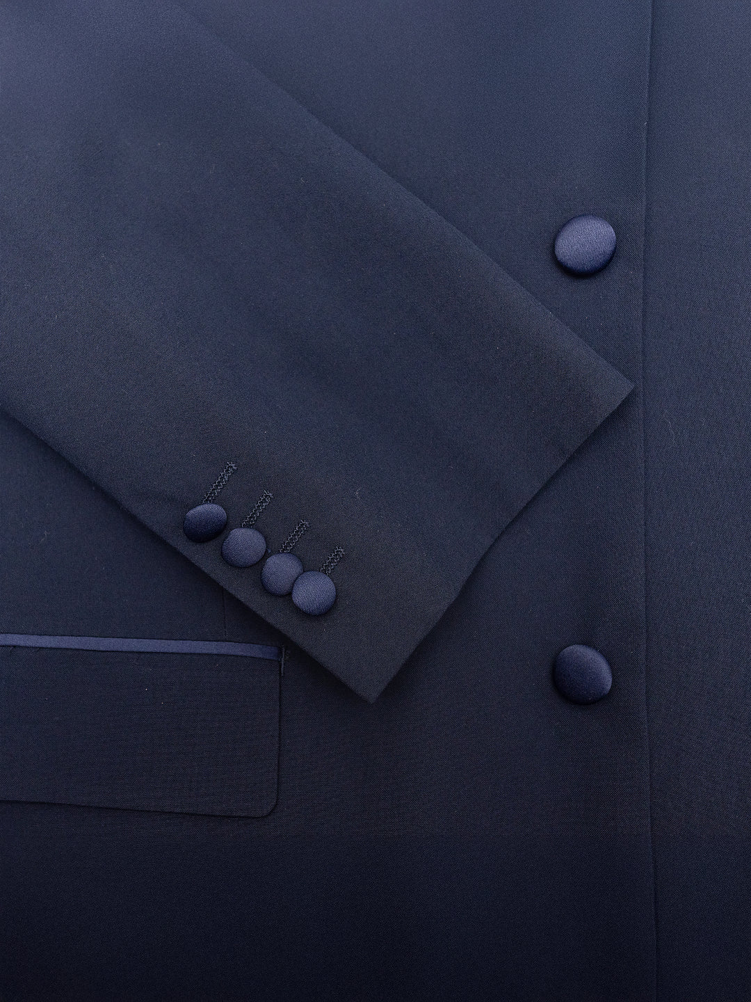 Close-up of the FUBU Classic Notch Lapel Navy Slim-Fit Tuxedo by Fubu The Colle, crafted from Tetron Rayon, showcasing a sleeve with four buttons and intricate pocket detail.