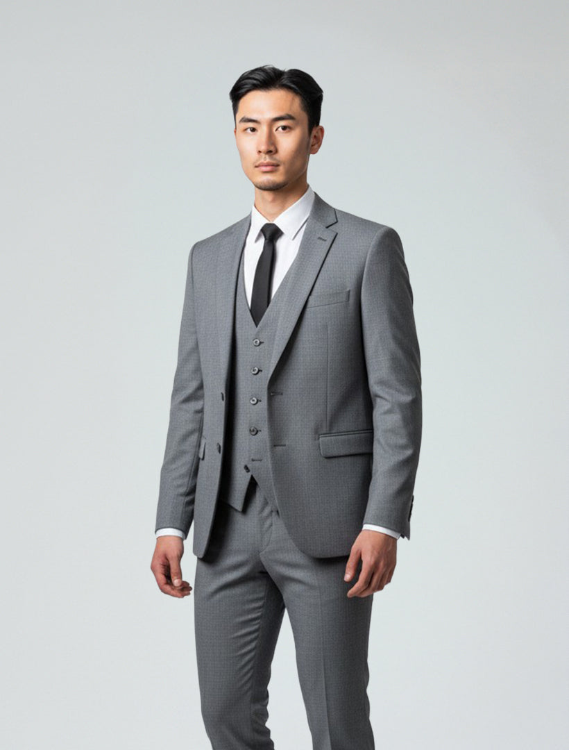 A man wears a Gino Vitale Men's Medium Grey Slim Fit Suit with a white dress shirt and black tie, standing against a plain light background.
