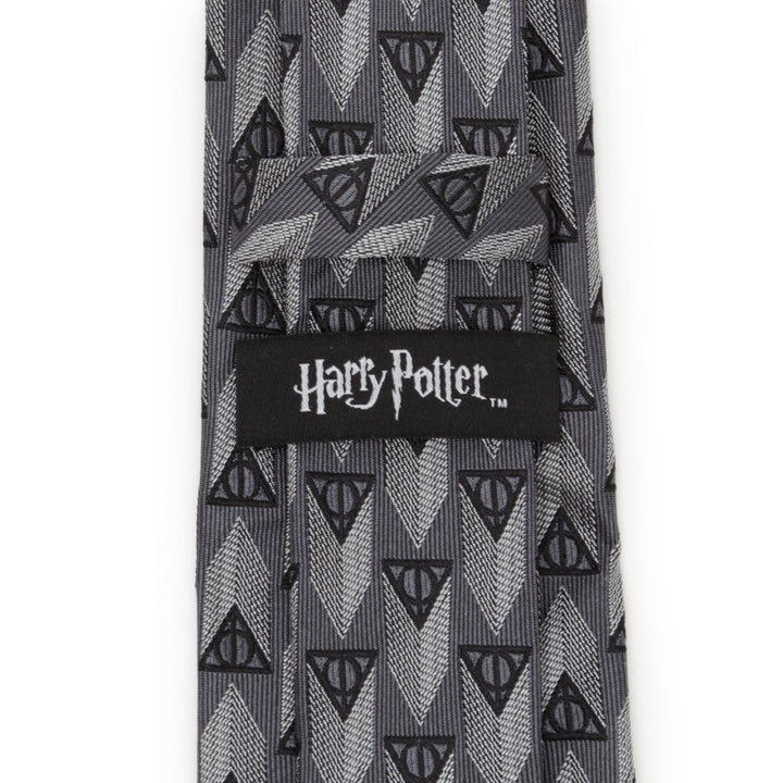 Gray Harry Potter Deathly Hallows Gray Silk Men’s Tie with a repeating Deathly Hallows symbol pattern and a Cufflinks.com brand label on the back.