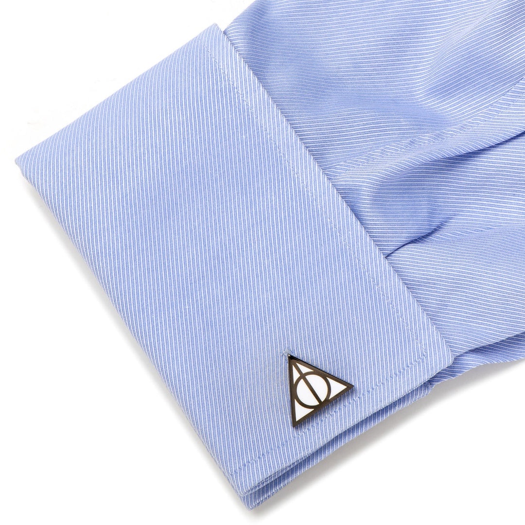 A metal Harry Potter Deathly Hallows Cufflinks set on a light blue dress shirt cuff.