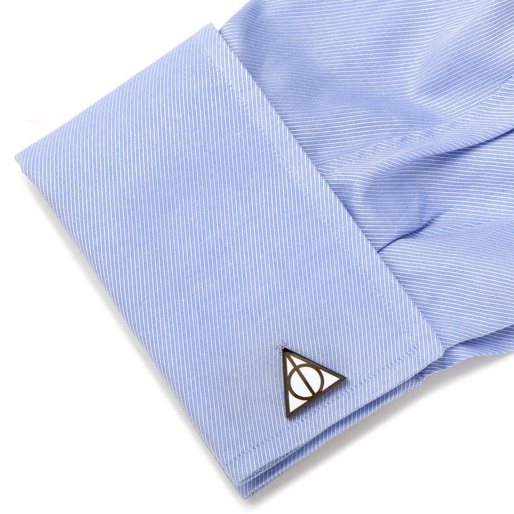 A metal Harry Potter Deathly Hallows Cufflinks set on a light blue dress shirt cuff.