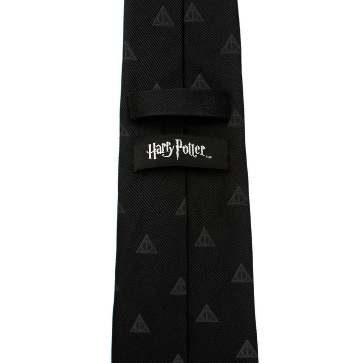Black silk Harry Potter Deathly Hallows Tie featuring a repeating pattern and a branded label on the back.