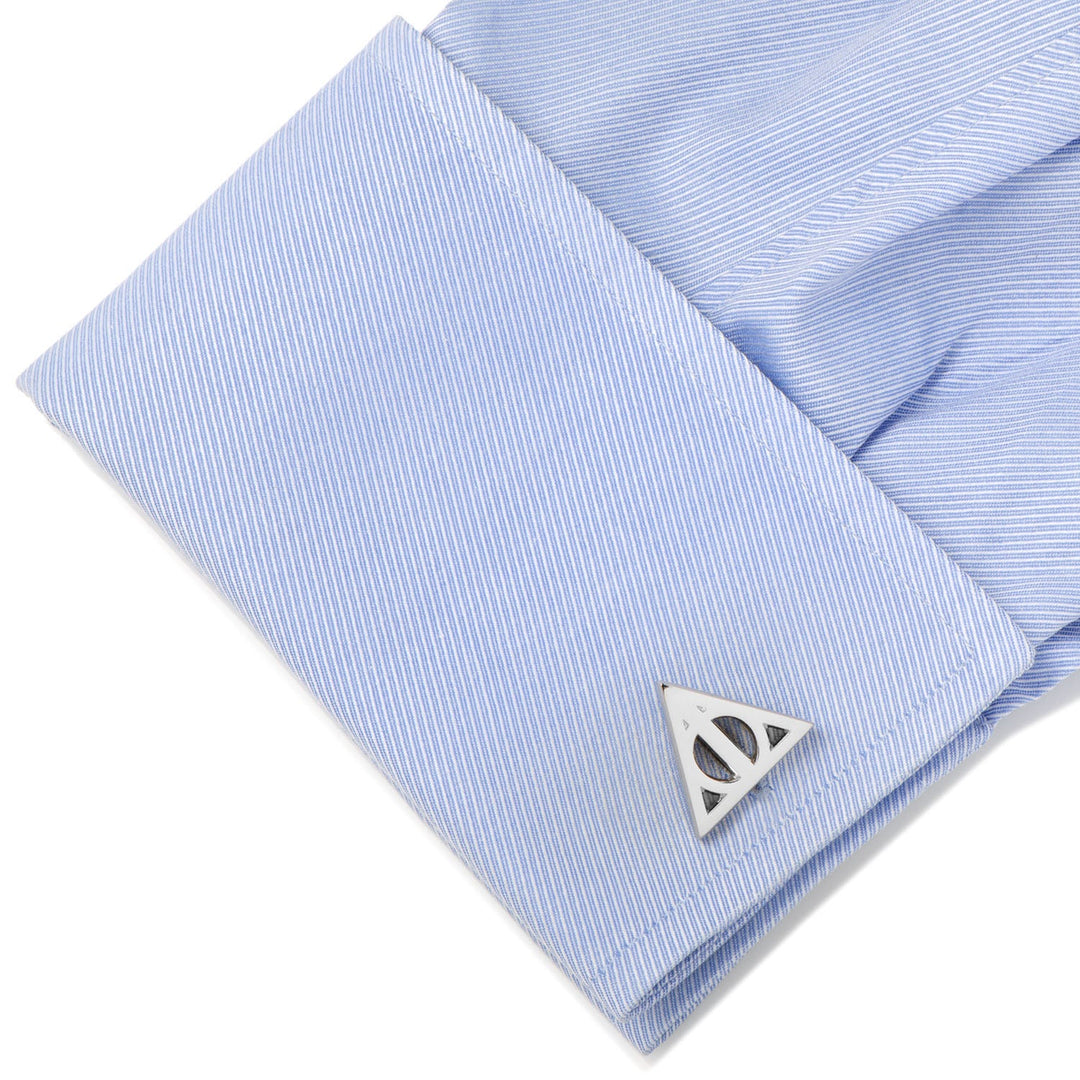 Silver-toned Deathly Hallows cufflink from the Harry Potter Deathly Hallows Gray Necktie Gift Set fastened to a light blue pinstriped French cuff.