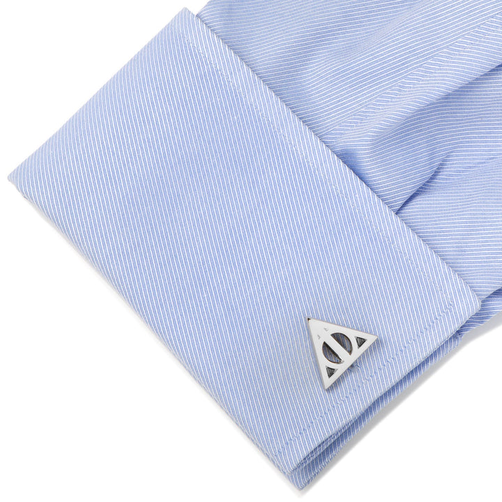 Silver-toned Deathly Hallows cufflink from the Harry Potter Deathly Hallows Gray Necktie Gift Set fastened to a light blue pinstriped French cuff.