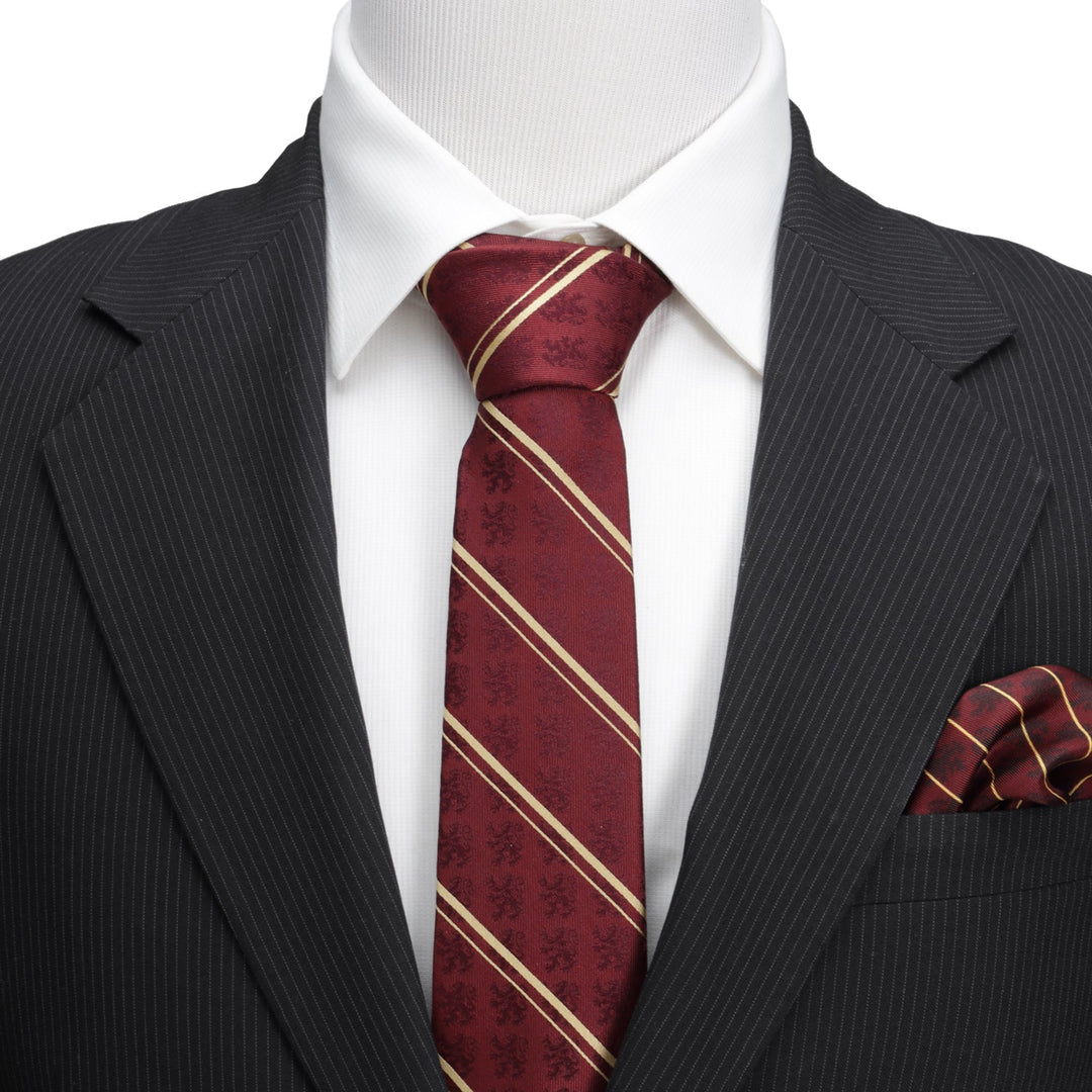 A Harry Potter Gryffindor Maroon Stripe Silk Men’s Tie with thin diagonal gold stripes and subtle lion patterns, worn with a white collared shirt, black pinstriped suit jacket, and matching pocket square.