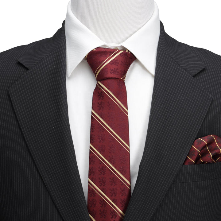A Harry Potter Gryffindor Maroon Stripe Silk Men’s Tie with thin diagonal gold stripes and subtle lion patterns, worn with a white collared shirt, black pinstriped suit jacket, and matching pocket square.