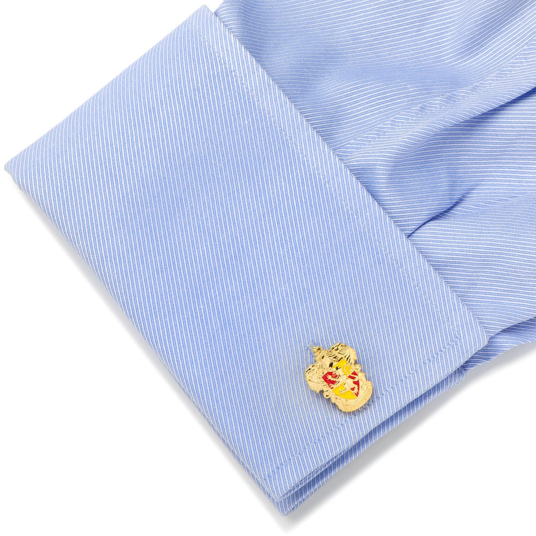 A gold-toned Harry Potter Gryffindor Crest Cufflinks lion crest attached to a light blue dress shirt sleeve.